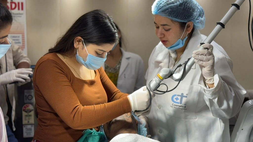 A dermatologist in a white coat applies a low-level laser therapy probe during a clinical consultation, illustrating MLA's bedside practice focus.